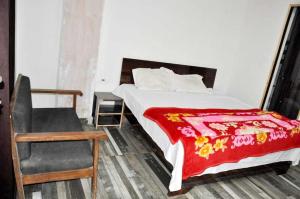 1 dormitorio con 1 cama con manta roja y silla en OYO The Moonshine Hotel, en Charkhi Dādri