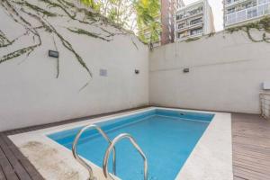 una pequeña piscina con una silla junto a un edificio en Hermoso Studio en Recoleta con Piscina y Laundry en Buenos Aires