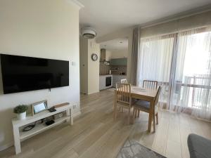 a living room with a table and a television on a wall at Baltica Sea Apartment in Gdańsk