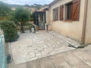 un patio de piedra frente a una casa en maison rez de jardin 2 à 4 personnes, en Le Lavandou