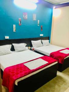 2 camas en una habitación con una pared azul en OYO The Bliss Guest House & Restaurant, en Gwalior