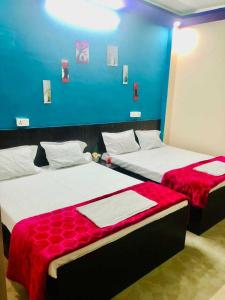 two beds in a room with a blue wall at OYO The Bliss Guest House & Restaurant in Gwalior