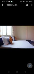 een slaapkamer met een wit bed met kussens en een raam bij Hotel Chalukya Executive in Pune