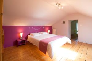 a bedroom with a large bed with a purple wall at Maison d'Hotes ZEN in La Saunière