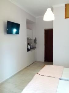 a white room with a bed and a flat screen tv at Studios Thomas in Limenaria