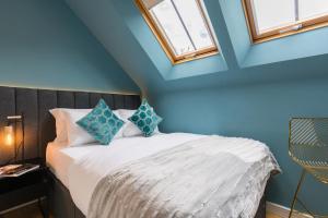Schlafzimmer mit einem Bett mit blauen Wänden und Fenstern in der Unterkunft Oakfield Premier Apartments - Fast Wifi - 5 mins City Centre in Cardiff
