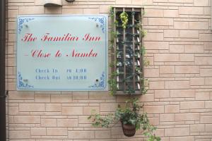 大阪市にあるThe Familiar Inn ー 旅館ホテル業の煉瓦壁の側面の看板