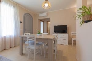 a dining room with a table and chairs and a television at Villa dei Pini Capoliveri in Capoliveri