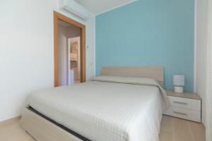 a white bedroom with a white bed and a nightstand at Villa dei Pini Capoliveri in Capoliveri