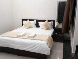 ein Schlafzimmer mit einem großen Bett mit weißer Bettwäsche und Kissen in der Unterkunft OYO Vasu Hotel in Alwar