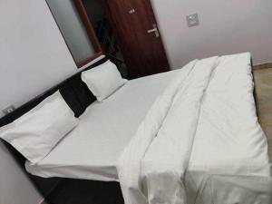 ein Bett mit weißer Bettwäsche auf einem Zimmer in der Unterkunft OYO Vasu Hotel in Alwar
