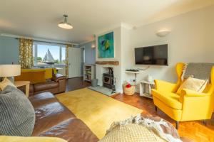 a living room with yellow furniture and a tv at High View in Wells next the Sea
