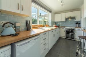 a kitchen with white cabinets and a counter top at High View in Wells next the Sea