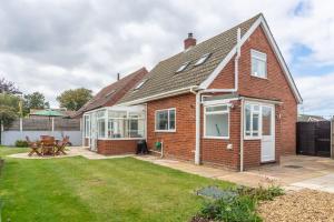 a brick house with a patio and a yard at High View in Wells next the Sea