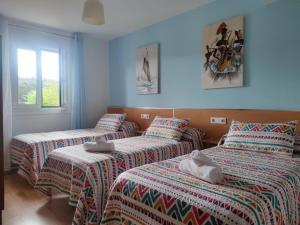 a room with three beds with towels on them at Apartamentos turísticos Lemos in Pedrouzo