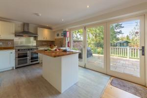 a kitchen with white cabinets and a large window at Kittiwake Cottage in Brancaster