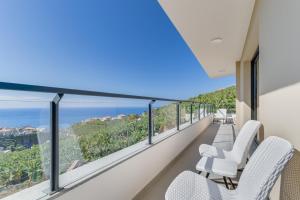 a balcony with white chairs and a view of the ocean at Banana Tree in Câmara de Lobos