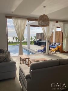 sala de estar con sofá y piscina en Casa GAIA - Punta Sal en Canoas De Punta Sal