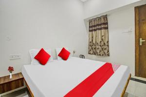 ein Schlafzimmer mit einem großen weißen Bett mit roten Kissen in der Unterkunft Flagship Crossroad Rooms in Nagpur