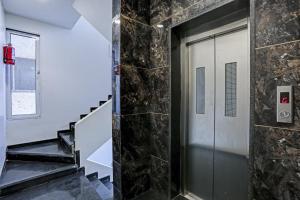 pasillo con puerta de cristal y pared de piedra en Capital O Hotel Calista, en Bombay