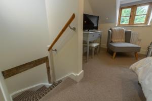 ein Schlafzimmer mit einer Treppe mit einem Schreibtisch und einem Stuhl in der Unterkunft Jasmine Cottage in South Creake