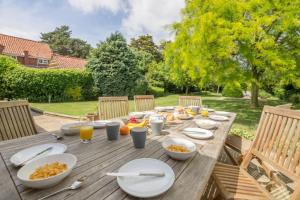 a wooden table with plates of food on it at Westgate Cottage T 4 in Thornham