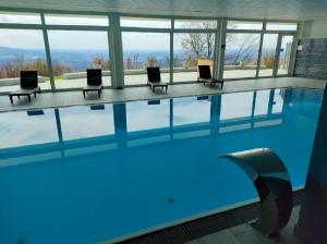 a large swimming pool with chairs and blue water at Traumblick Bayerischer Wald, Pool & Sauna, Getränke, Klimaanlage in Freyung