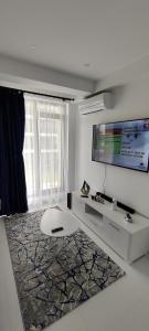 a white living room with a tv and a couch at Euphoria Neptun Oxygen in Neptun