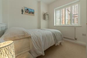 a white bedroom with a bed and a window at Seahorses in Brancaster