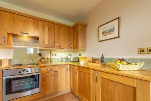 a kitchen with wooden cabinets and a bowl of fruit on the counter at Ludham Hall Cottage in Ludham