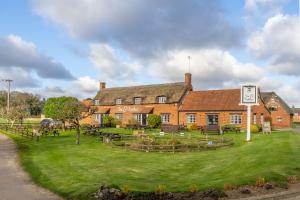 a large red brick building with a green yard at Ludham Hall Cottage in Ludham