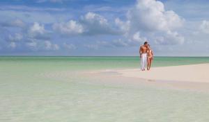 a man and a woman walking on a beach at Grand Oasis Tulum Riviera - All Inclusive in Akumal