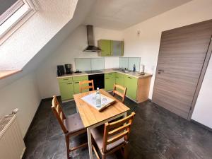 eine Küche mit grünen Schränken sowie einem Holztisch und Stühlen in der Unterkunft Ferienwohnung Harzdomizil in Gernrode - Harz