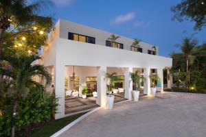a white house with a lot of plants in front of it at Grand Oasis Tulum Riviera - All Inclusive in Akumal