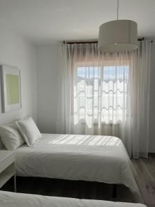 Habitación blanca con cama y ventana en Casa Batea, en Moaña