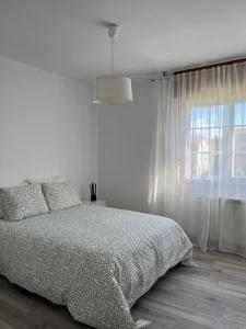 Habitación blanca con cama y ventana en Casa Batea, en Moaña