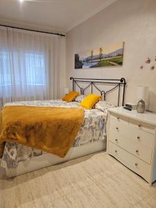 sypialnia z łóżkiem z żółtymi poduszkami i komodą w obiekcie Mar Vista w Sant Antoni de Calonge