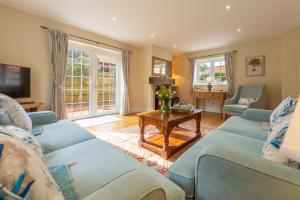 a living room with blue couches and a table at 1 Hall Lane Cottages in Thornham