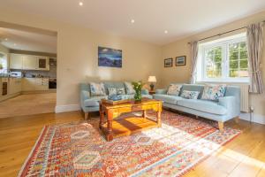 un soggiorno con 2 divani blu e un tavolo di 1 Hall Lane Cottages a Thornham
