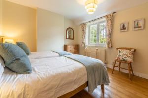 a bedroom with a bed and a window and a chair at 1 Hall Lane Cottages in Thornham