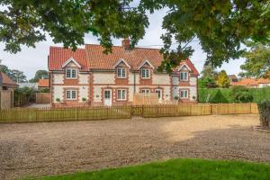 una grande casa in mattoni rossi con una recinzione in legno di 1 Hall Lane Cottages a Thornham