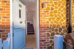 una casa de ladrillo con una puerta azul y una pared de ladrillo en The Malthouse, en Dersingham