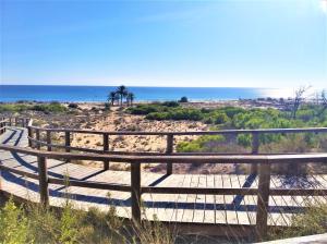een houten pad naar het strand met de oceaan op de achtergrond bij El Bungalow de Javi in Gran Alacant