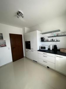 eine Küche mit weißen Schränken und einer braunen Tür in der Unterkunft Ferienwohnung Pfungstadt in Pfungstadt