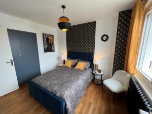 um quarto com uma cama azul e uma cadeira branca em La suite du Theatre em Bourges