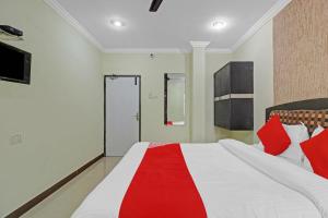 um quarto com uma cama grande e almofadas vermelhas e brancas em Super OYO Flagship Hotel Kanak International em Hyderabad