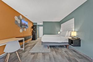 a bedroom with a bed and a desk and a chair at Buffalo Airport Hotel in Cheektowaga