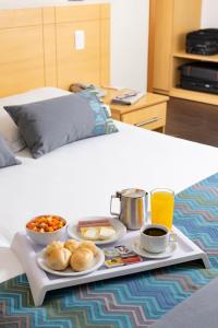 a tray with food and drinks on a bed at Monreale Plus Guarulhos International Airport in Guarulhos