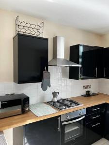 a kitchen with a stove top oven next to a microwave at No.2 Beechcroft / Park-Side / Ping Pong & Garden in Liverpool