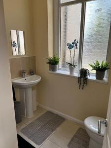 a bathroom with a sink and a toilet and a window at No.2 Beechcroft / Park-Side / Ping Pong & Garden in Liverpool